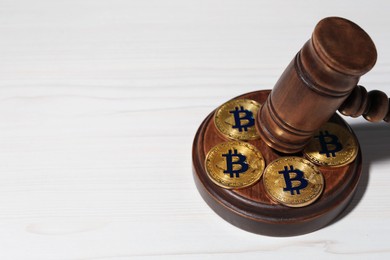 Photo of Cryptocurrency. Bitcoins and judge's gavel on white wooden table, closeup. Space for text