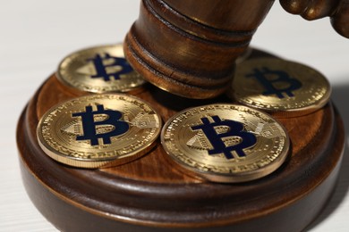 Photo of Cryptocurrency. Bitcoins and judge's gavel on white table, closeup