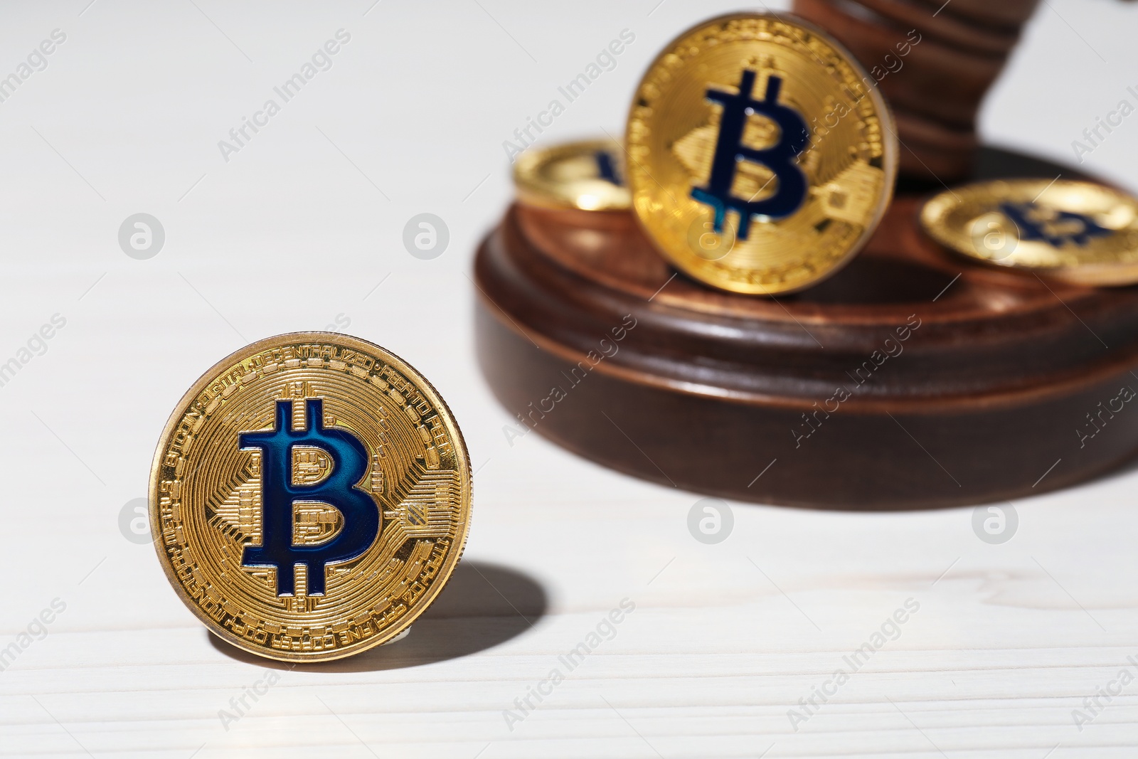 Cryptocurrency. Bitcoins and judge's gavel on white wooden table, closeup Photo of Cryptocurrency. Bitcoins and judge's gavel on white wooden table, closeup