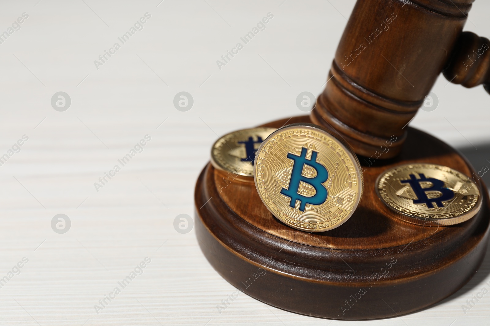 Photo of Cryptocurrency. Bitcoins and judge's gavel on white wooden table, closeup. Space for text