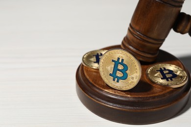 Photo of Cryptocurrency. Bitcoins and judge's gavel on white wooden table, closeup. Space for text