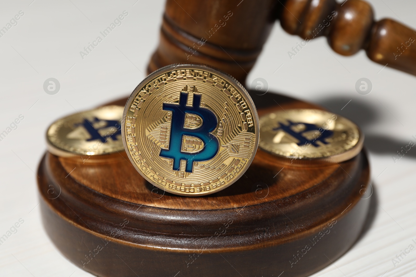 Cryptocurrency. Bitcoins and judge's gavel on white table, closeup Photo of Cryptocurrency. Bitcoins and judge's gavel on white table, closeup