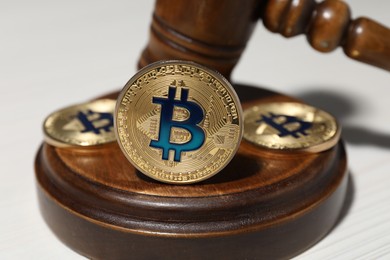Photo of Cryptocurrency. Bitcoins and judge's gavel on white table, closeup