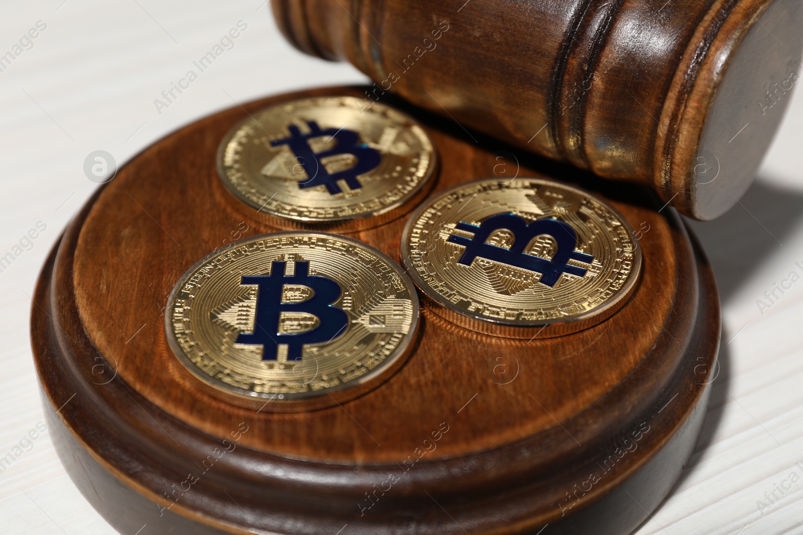 Cryptocurrency. Bitcoins and judge's gavel on white table, closeup Photo of Cryptocurrency. Bitcoins and judge's gavel on white table, closeup