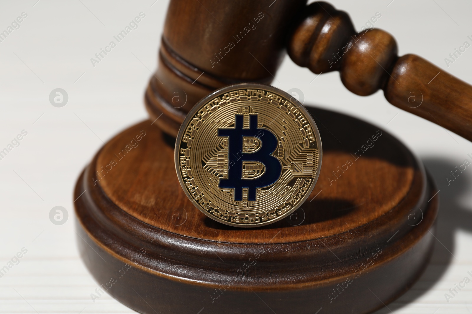 Cryptocurrency. Bitcoins and judge's gavel on white table, closeup Photo of Cryptocurrency. Bitcoins and judge's gavel on white table, closeup