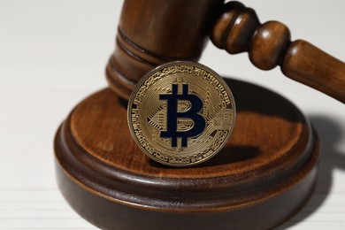 Photo of Cryptocurrency. Bitcoins and judge's gavel on white table, closeup