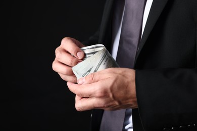Photo of Man with dollar bills on black background, closeup