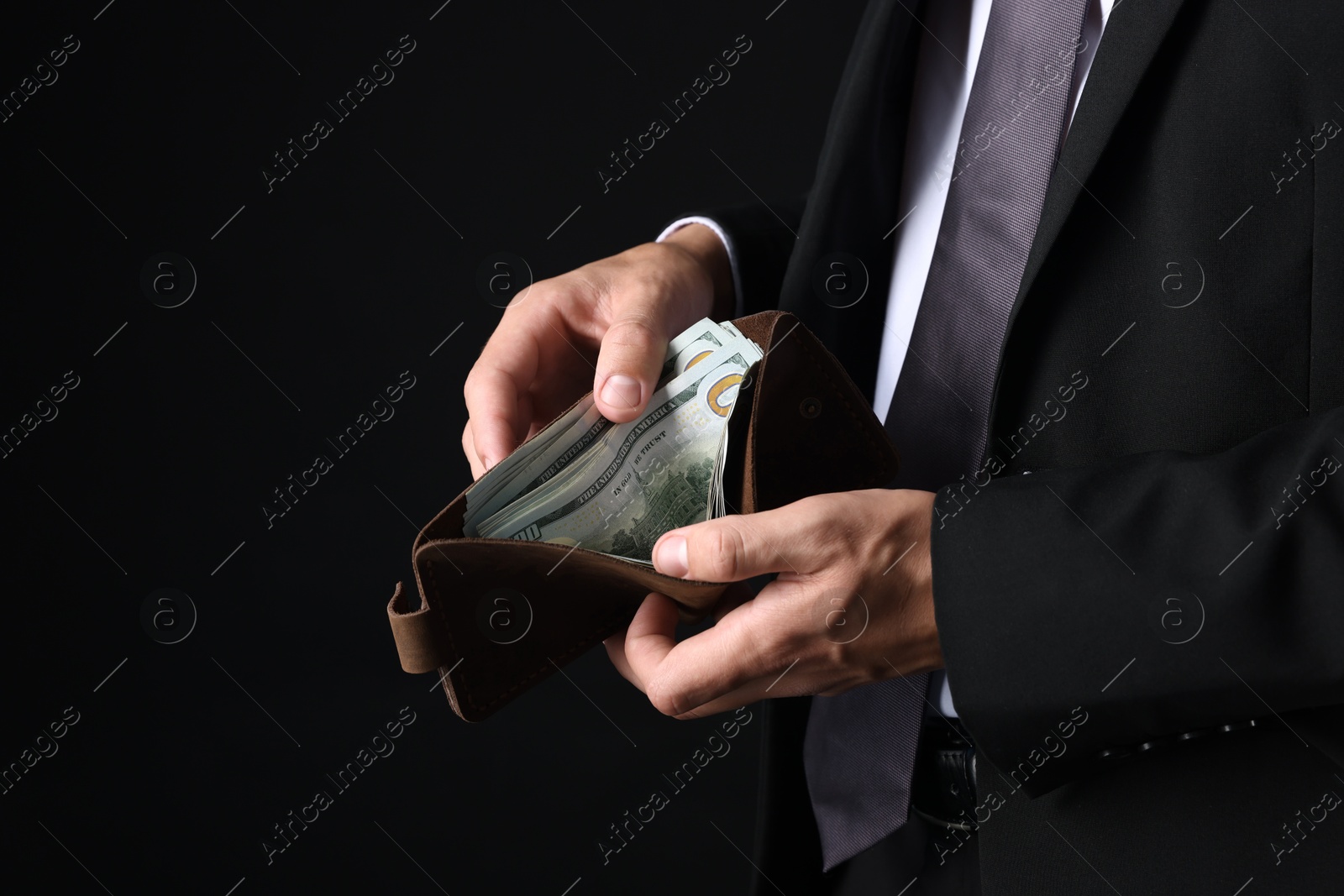 Man holding wallet with dollars on black background, closeup. Space for text Photo of Man holding wallet with dollars on black background, closeup. Space for text