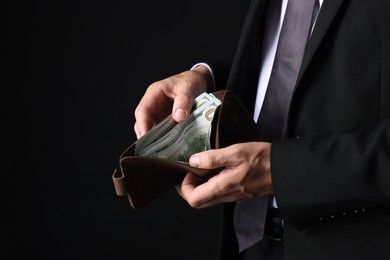 Photo of Man holding wallet with dollars on black background, closeup. Space for text
