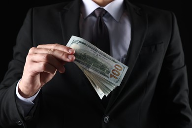 Photo of Man with dollar bills on black background, closeup