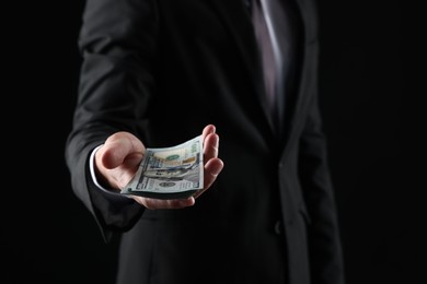 Photo of Man with dollar bills on black background, closeup
