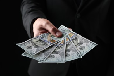 Photo of Man with dollar bills on black background, closeup