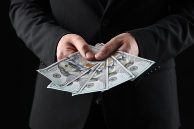 Photo of Man with dollar bills on black background, closeup