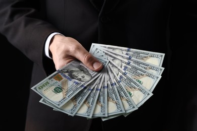 Photo of Man with dollar bills on black background, closeup