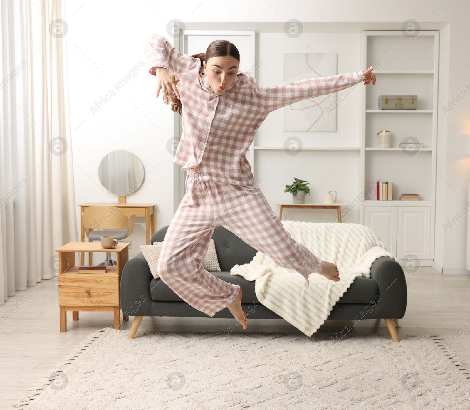 Beautiful woman in pyjama jumping at home Photo of Beautiful woman in pyjama jumping at home