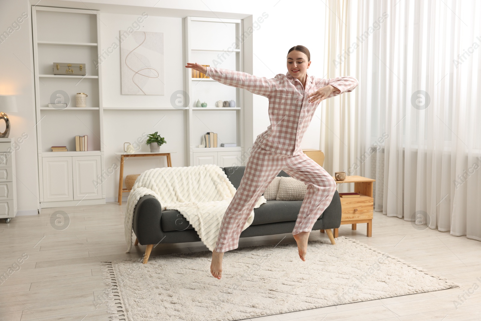 Happy woman in pyjama jumping at home, space for text Photo of Happy woman in pyjama jumping at home, space for text