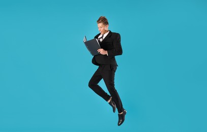 Photo of Businessman with folder jumping on light blue background