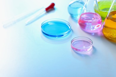 Photo of Laboratory glassware with different samples on light table, closeup. Space for text