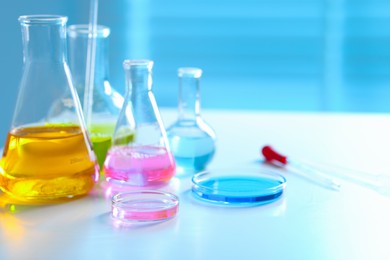 Photo of Laboratory glassware with different samples on light table, closeup. Space for text