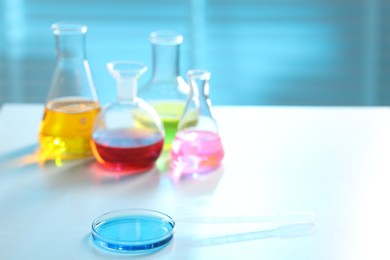 Photo of Laboratory glassware with different samples on light table, closeup. Space for text