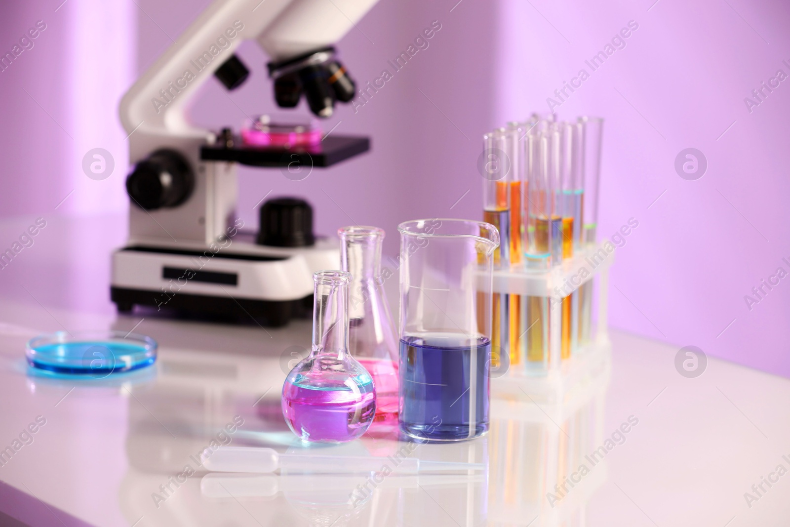 Photo of Laboratory glassware with different samples and microscope on light table