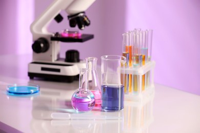 Photo of Laboratory glassware with different samples and microscope on light table