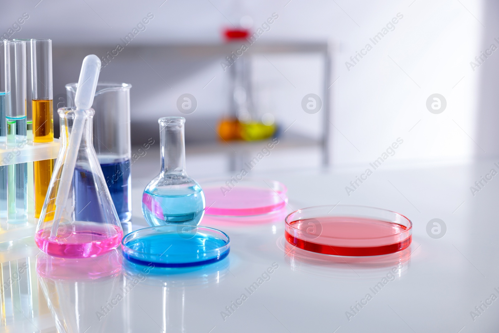 Photo of Laboratory glassware with different samples on light table, closeup. Space for text