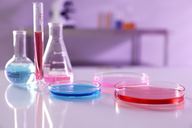 Photo of Laboratory glassware with different samples on light table, closeup. Space for text
