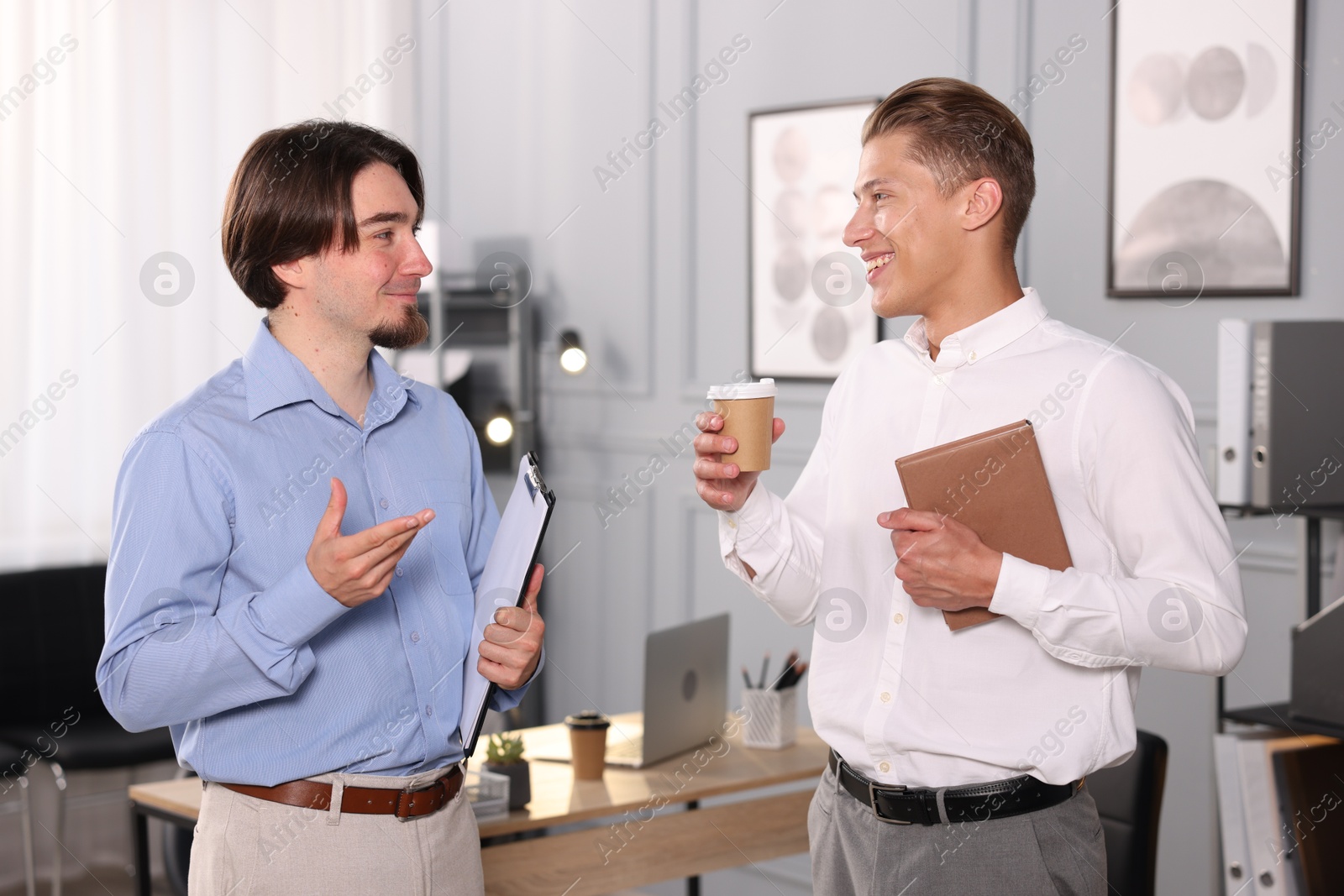 Coworkers with paperwork, coffee and tablet having conversation in office Photo of Coworkers with paperwork, coffee and tablet having conversation in office