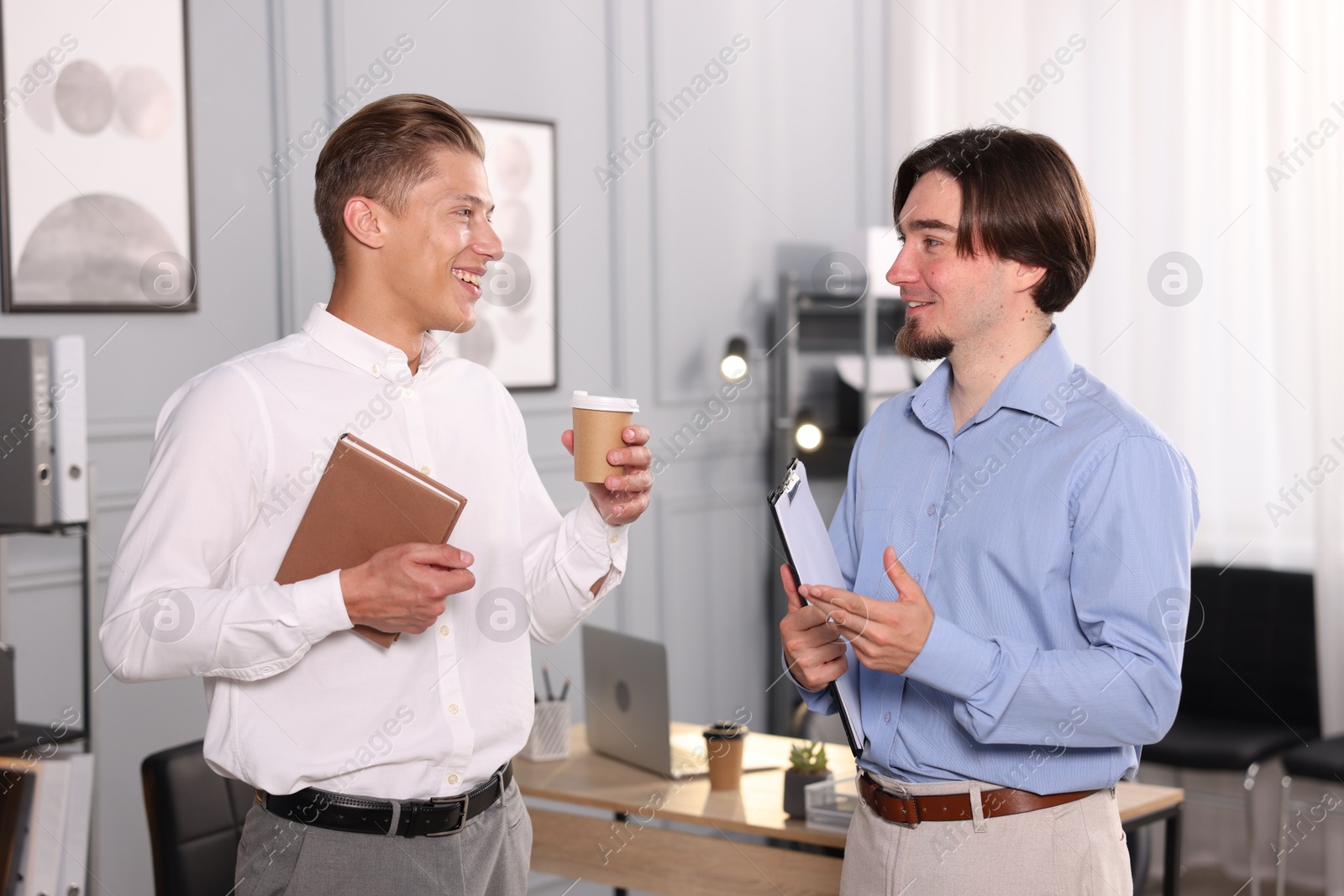 Coworkers with paperwork, coffee and tablet having conversation in office Photo of Coworkers with paperwork, coffee and tablet having conversation in office
