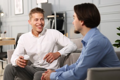 Photo of Man having conversation with his coworker during coffee break in office