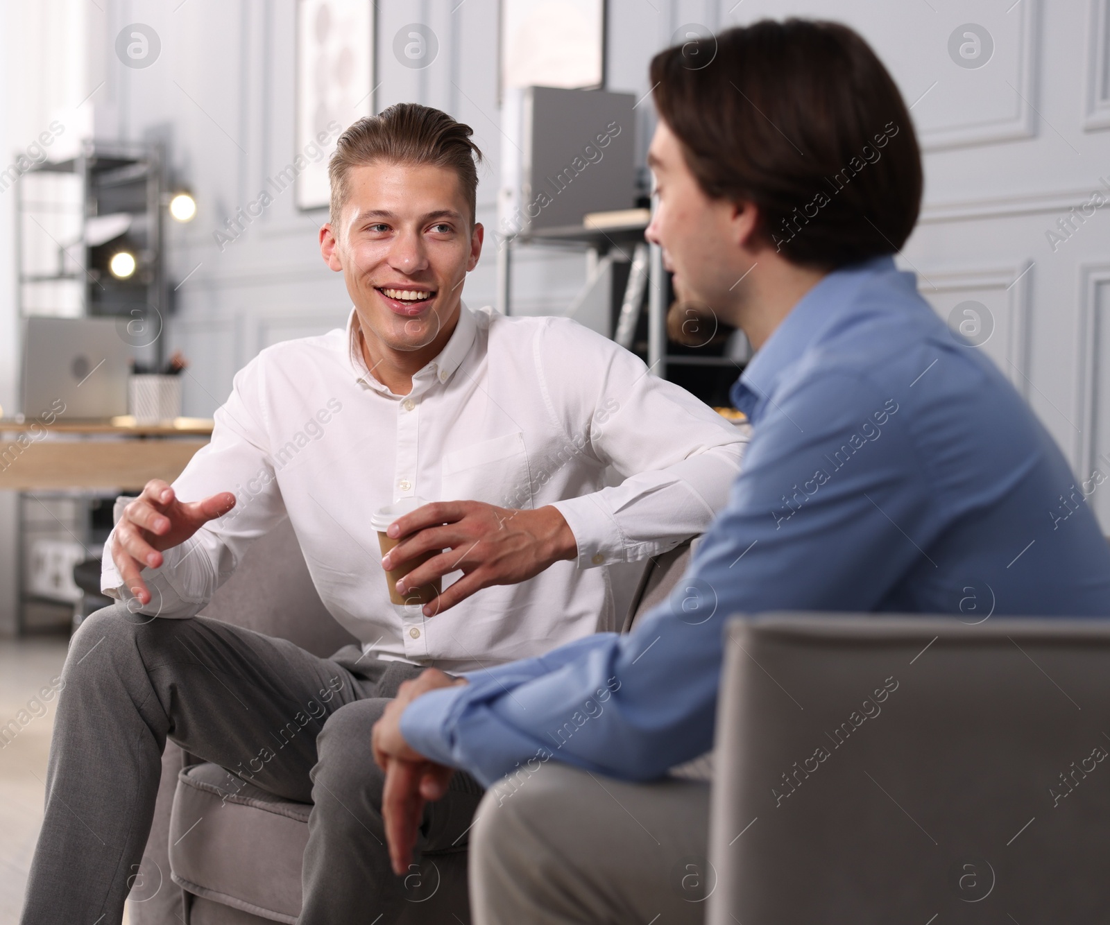 Photo of Man having conversation with his coworker during coffee break in office