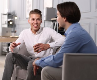 Photo of Man having conversation with his coworker during coffee break in office