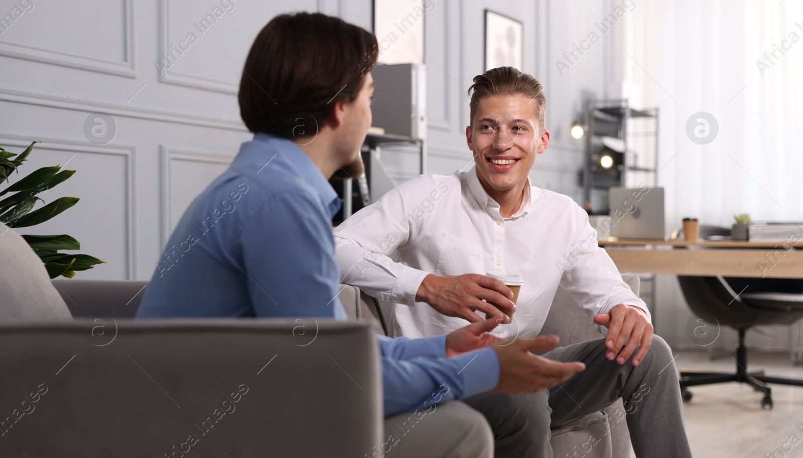 Photo of Man having conversation with his coworker during coffee break in office