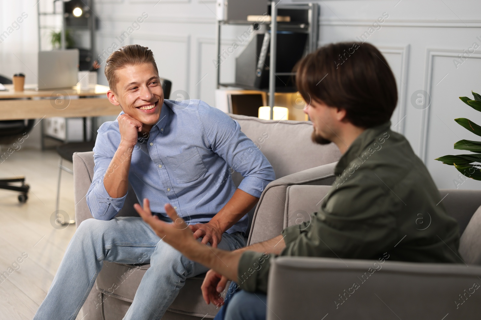 Photo of Colleagues having conversation during break in armchairs at office