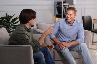 Photo of Colleagues having conversation during break in armchairs at office