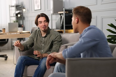 Photo of Colleagues having conversation during break in armchairs at office