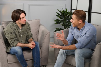 Photo of Colleagues having conversation during break in armchairs at office