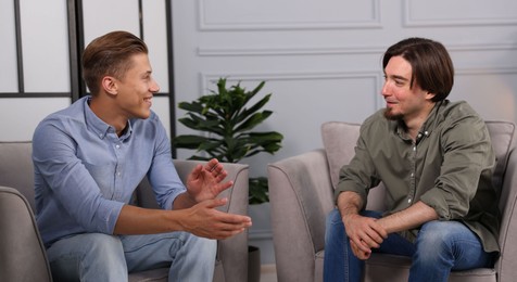 Photo of Colleagues having conversation during break in armchairs at office