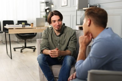Photo of Colleagues having conversation during break in armchairs at office