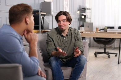 Photo of Colleagues having conversation during break in armchairs at office