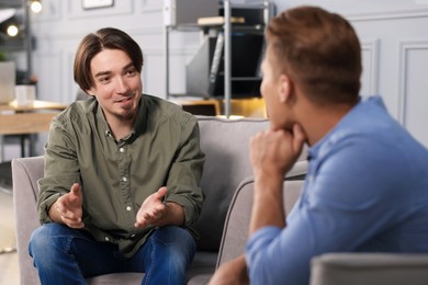 Photo of Colleagues having conversation during break in armchairs at office