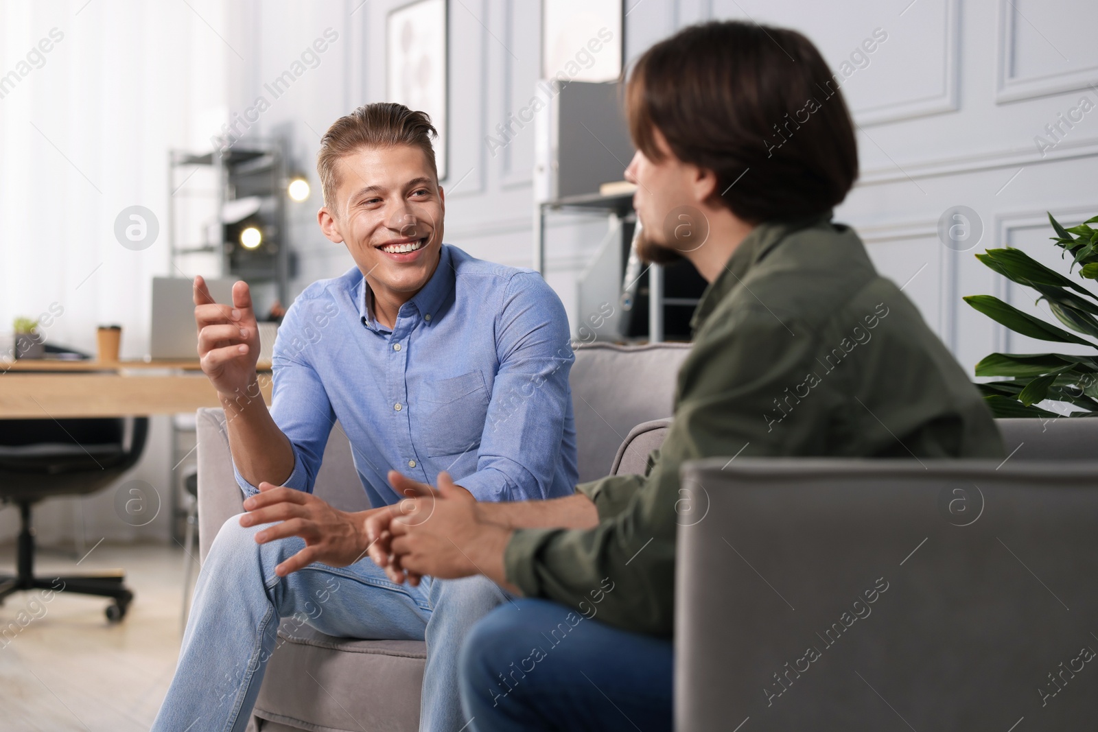 Photo of Colleagues having conversation during break in armchairs at office