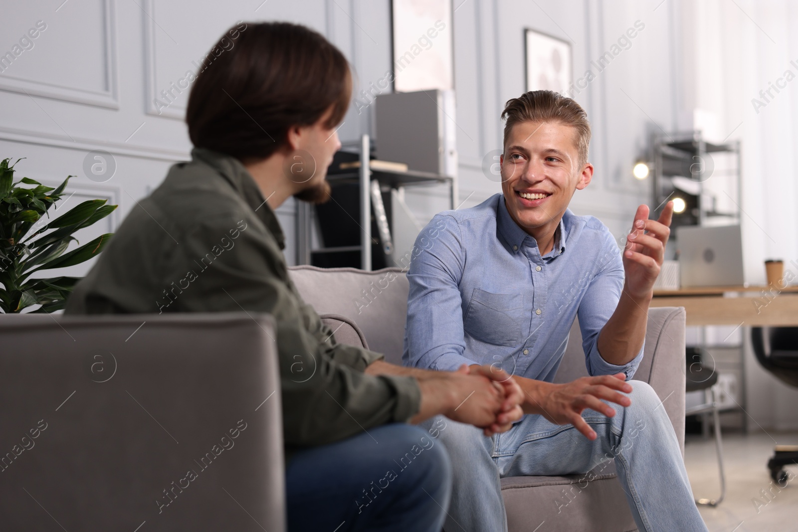 Photo of Colleagues having conversation during break in armchairs at office