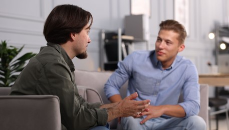 Photo of Colleagues having conversation during break in armchairs at office
