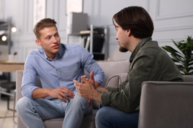 Photo of Colleagues having conversation during break in armchairs at office