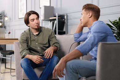 Photo of Colleagues having conversation during break in armchairs at office