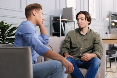 Photo of Colleagues having conversation during break in armchairs at office