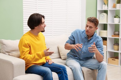 Photo of Friends having conversation on sofa at home