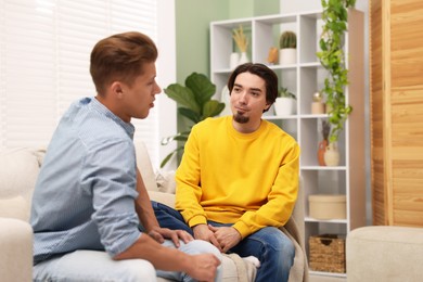 Photo of Friends having conversation on sofa at home